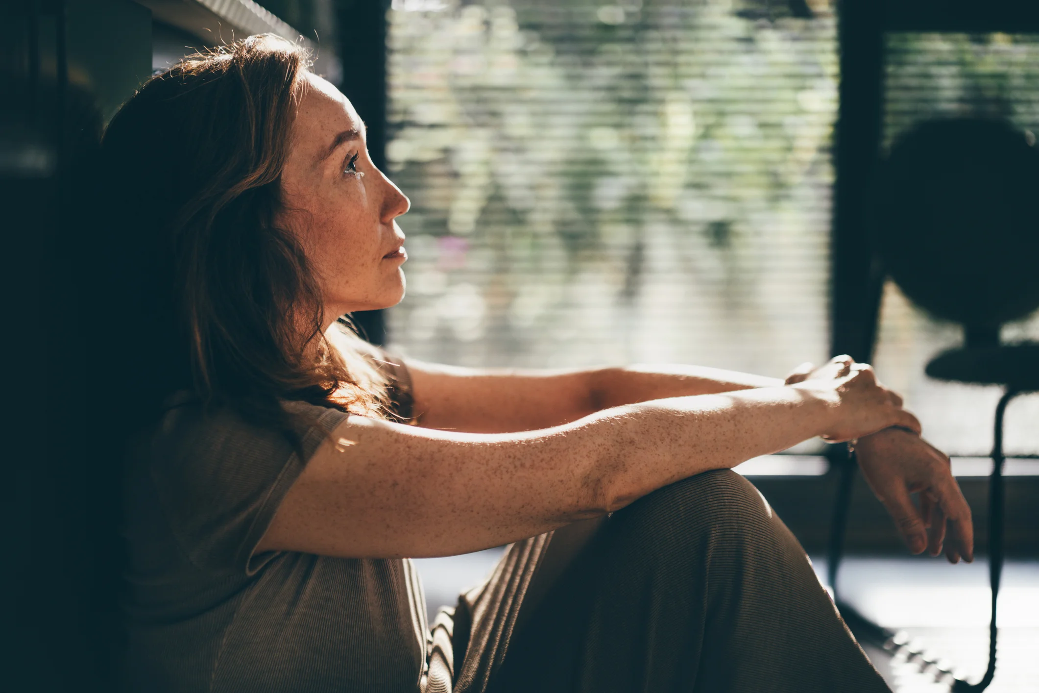 Depressed woman sitting on the floor in the kitchen.