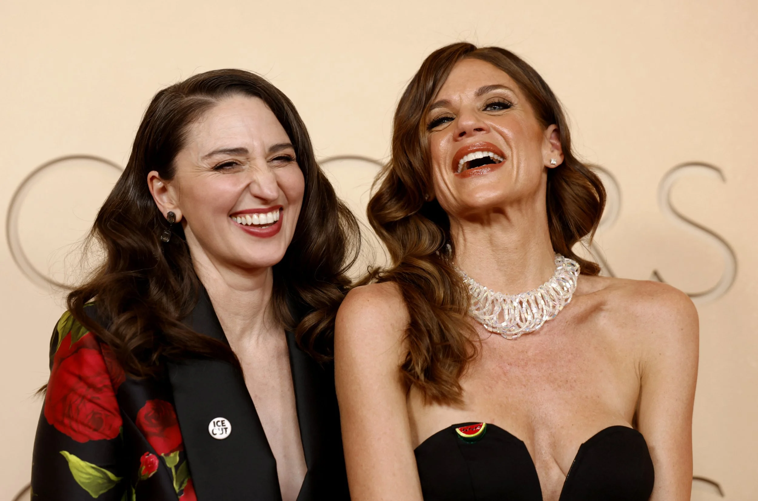 Sara Bareilles wears a pin reading "Ice Out" as she and a guest wearing a watermelon-shaped pin pose on the red carpet during the Oscars arrivals at the 98th Academy Awards in Hollywood, Los Angeles, California, U.S., March 15, 2026. REUTERS/Caroline Brehman